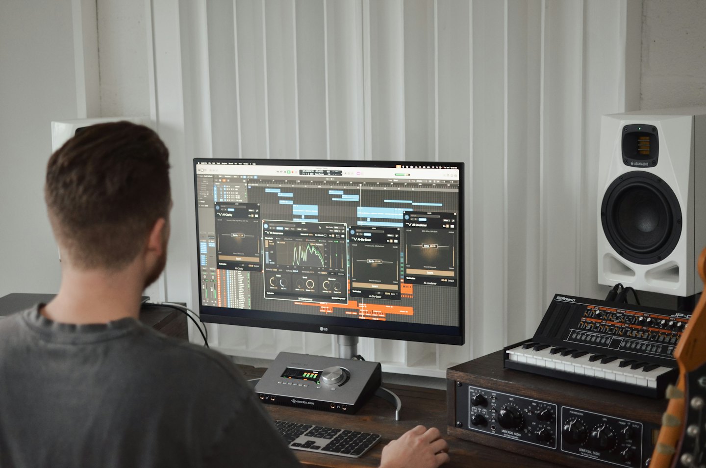 Persona lavora al software di produzione musicale su una scrivania in uno studio casalingo.